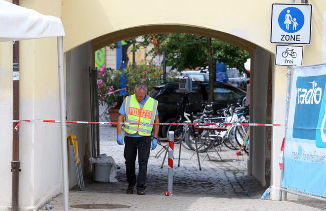 A member of the German police stands behind a police tape in Ansbach, Germany, Monday, near the site where a failed asylum-seeker from Syria blew himself up and wounded 15 people after being turned away from an open-air music festival in southern Germany.