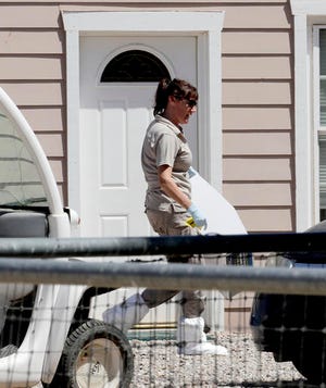 A crime scene investigator works outside a home where multiple bodies were found, Tuesday, July 26, 2016, in Gilbert, Ariz. Sheriff's officials say multiple dead bodies have been found inside a home in an unincorporated area of Gilbert, east of Phoenix. There's no immediate word Tuesday on how many bodies or their ages or genders. (AP Photo/Matt York)