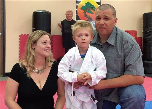 Liam Brenes, 4, with his parents, Amanda McFarland, and Frank Brenes at United Karate studio in Mission Viejo, Calif., on Tuesday, July 26, 2016. Brenes had his custom prosthetic leg stolen at Crystal Cove State Park on Sunday, but was able to earn his white belt by using his older prosthetic leg. When word got out, people started offering replacements or donations. An online campaign has raised more than $15,000. (Nick Koon/The Orange County Register via AP)