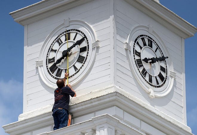 Carl Rickershauser measures the faces of the clock towers at Rancocas Valley Regional High School in Mount Holly, where he is doing restoration work.