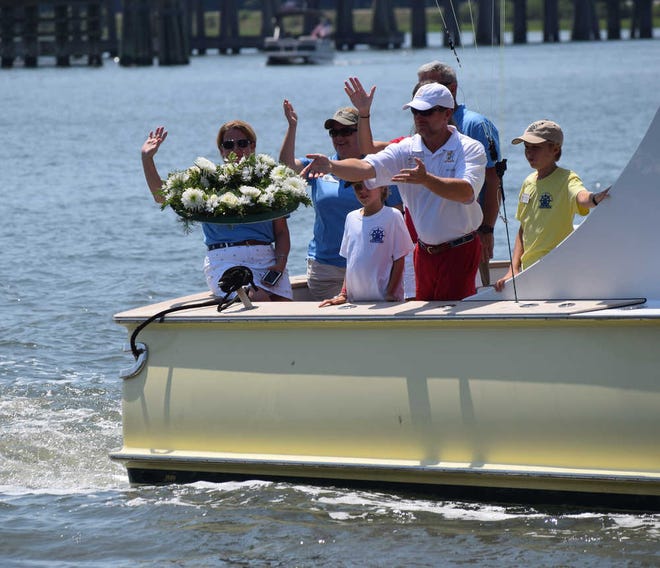 Jessicah Lawrence/Beaufort Today Beaufort Water Festival Commodore Chris Canaday throws the wreath into the water at the blessing of fleet Sunday. The wreath represents all those who have died in the past year.