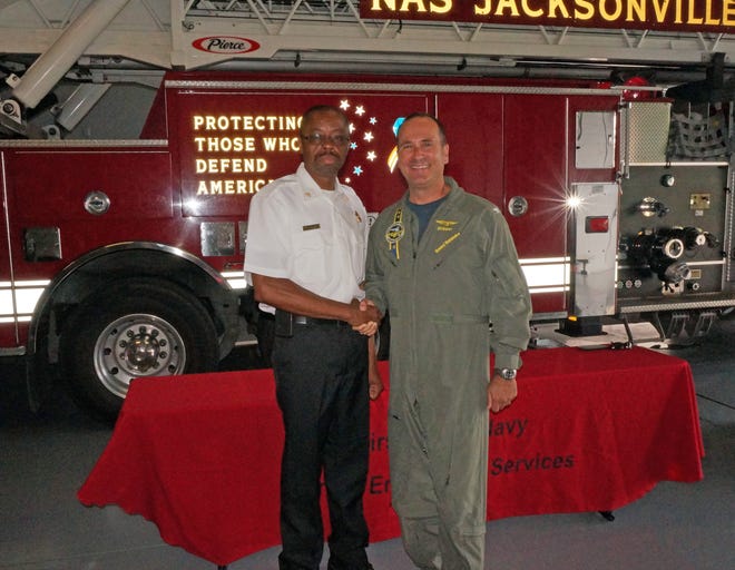 NAS Jacksonville Commanding Officer Capt. Howard Wanamaker congratulates NAS Jax new Chief of Fire Prevention Robert Winchester.