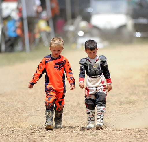 In this July 2, 2016 photo, Keegan McDade, right, walks with his friend Everett Rogan at the first annual Bikes, Bands and BBQ before competing in the PAMX Mini Motocross race at the High Voltage MX Park in Ford City, Pa. Keegan, who was diagnosed with acute lymphoblastic leukemia, rides while undergoing chemotherapy treatments. His family has established Keegan's Krew to raise money for research to support other children diagnosed with leukemia. (Pam Panchak /Pittsburgh Post-Gazette via AP)