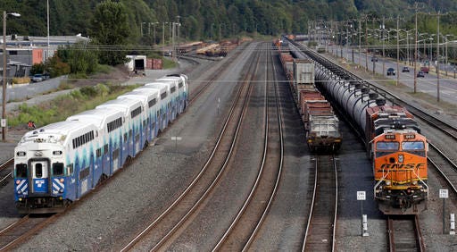 FILE - In this July 27, 2015, file photo, a passenger commuter train, left, passes one of two mile-long oil trains parked adjacent to the King County Airport in Seattle. As oil trains began rolling through its downtown a few years ago, Spokane, Wash, was among the first cities to pass a resolution calling for tougher state and federal safety regulations. But when an oil train derailed in a fiery crash in Oregon last month, after earlier rumbling through the Eastern Washington city, some city leaders didn't want to wait for the federal government to act. The Spokane City Council decided 6-0 to ask voters whether the city should fine companies that ship crude oil or coal by rail through downtown, Wednesday, July 27, 2016. (AP Photo/Elaine Thompson, File)