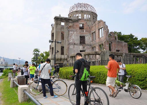 In this July 26, 2016 photo, people play Pokemon Go near the Atomic Bomb Dome at Hiroshima Peace Memorial Park in Hiroshima, Japan. Pokemon Go” players are descending on an atomic bomb memorial park in Hiroshima, and officials of the western Japanese city are displeased. They have asked game developer Niantic Inc. to remove the “Pokestops” and other virtual sites that show up in the park for those playing the augmented reality game. The city wants them deleted by Aug. 6, the anniversary of the 1945 bombing and the date of an annual ceremony to remember the victims. (Kyodo News via AP)