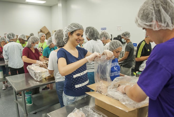 Luisa Oliva, 16, a high school student from Brazil, packages frozen pork chops with Hickman High School sophomore Austin Wilson, right, Wednesday at The Food Bank for Central & Northeast Missouri. Students from Brazil and South Korea visited the University of Missouri to explore careers and the university during a two-week program