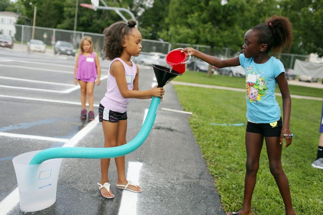 Ericka Conard, 8, dumps a bucket of water into a pool noodle as teammate and cousin Paige Conard, 7, keeps the funnel and noodle in place Wednesday during a stop at one of several stations in which Burlington Summer School students transferred water into a bucket at Corse Elementary School. The activity was part of a lesson about how water moves taught by a pre-kindergarten through 12th-grade coordinator from Iowa Public Television.