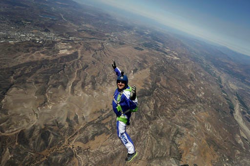 In this Monday, July 25, 2016 photo, skydiver Luke Aikins smiles as he jumps from a helicopter during his training in Simi Valley, Calif. After months of training, this elite skydiver says he's ready to leave his chute in the plane when he bails out 25,000 feet above Simi Valley on Saturday. That's right, no parachute, no wingsuit and no fellow skydiver with an extra one to hand him in mid-air. (AP Photo/Jae C. Hong)