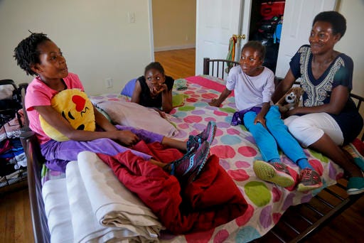 In this Wednesday, July 20, 2016 photo, Tonia Handy, far right, and her daughters, Rainn Sheppard, 10, far left, Tai Sheppard, 11, second from left, and Brooke Sheppard, 8, second from right, together in the bedroom of their apartment in a Brooklyn shelter, in New York. "Some families meet at the dinner table, we have these mattresses that were put together by two twin beds and that's our meeting place," said Handy. "We do everything in that bed. It's somewhere to connect." (AP Photo/Bebeto Matthews)