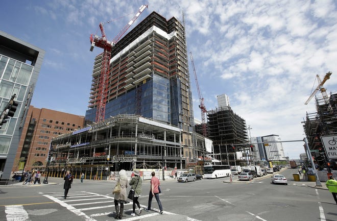 In this Thursday, May 19, 2016 photo, passers-by walk near the construction site a high-rise building in Boston. (AP Photo/Steven Senne)