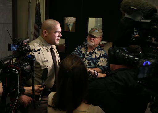 FILE - In this Monday, April 11, 2016 file photo, Vic Regalado, left, the new Tulsa County sheriff, is interviewed following his swear-in during the board of commissioners meeting at the Tulsa County Courthouse. An Oklahoma volunteer sheriff's deputy program shut down after a member fatally shot an unarmed black man is back in business with tougher requirements, new sheriff Vic Regalado said, although every one of the new reserves was in the old force riddled with cronyism and all but three are white in a city with fraught race relations. (Cory Young/Tulsa World via AP, File) /Tulsa World via AP) ONLINE OUT; KOTV OUT; KJRH OUT; KTUL OUT; KOKI OUT; KQCW OUT; KDOR OUT; TULSA OUT; TULSA ONLINE OUT; MANDATORY CREDIT