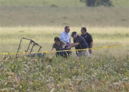The partial frame of a hot air balloon is visible above a crop field as investigators comb the wreckage of a crash Saturday, July 30, 2016, in Central Texas near Lockhart, Texas. Authorities say the accident caused a "significant loss of life." (Ralph Barrera/Austin American-Statesman via AP)