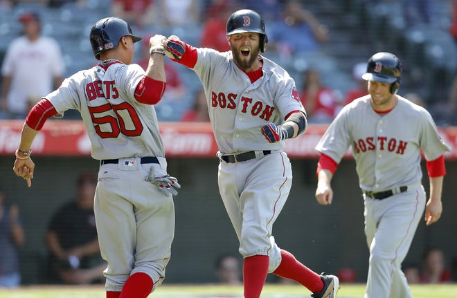 Dustin Pedroia, center, celebrates with Mookie Betts, left, after hitting a three-run home run that rallied the Red Sox past the Angels with two outs in the ninth inning on Sunday night. AP Photo