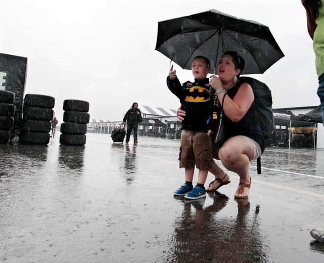 Cristin Guiher, of Bellefonte, Pa., listens to the rain as her 4-year-old son Colton Guiher points to race car haulers in the garage area at Pocono Raceway before the NASCAR Sprint Cup Series Pennsylvania 400 on Sunday in Long Pond, Pa. (AP Photo/Mel Evans)