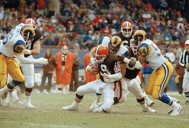 lCleveland Browns quarterback Bernie Kosar (19) is sacked by Kevin Greene of the Los Angeles Rams for a loss during the second quarter game in Cleveland, Dec. 3, 1990. (AP Photo/Jeff Glidden)