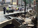 Workers gather by street damage after Saturday night's flooding in Ellicott City, Md., Sunday. Historic, low-lying Ellicott City was ravaged by floodwaters Saturday night, killing two people and causing devastating damage to homes and businesses, officials said.