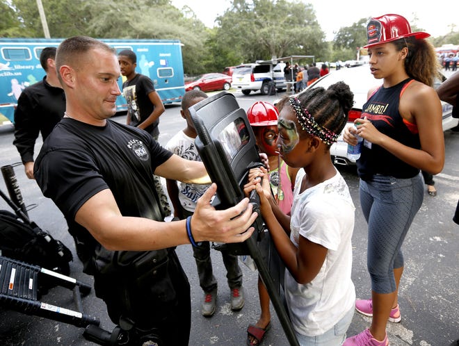 Cpl. Tommy Harrison, with the Gainesville Police Department SWAT team, demonstrates tactical gear with children during the annual National Night Out Against Crime at Lincoln Park on Tuesday. MATT STAMEY/STAFF PHOTOGRAPHER