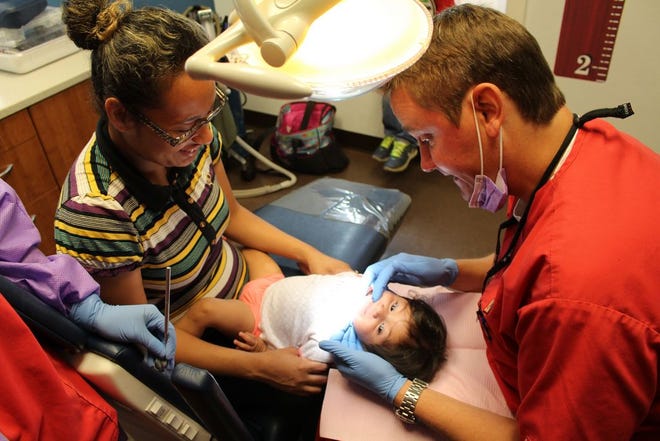 Maria Gonzalez tries to make her 11-month-old daughter Corazon Selbera, of Del Rio, Texas, smile as Dr. Howard Hunt examines her new teeth on July 11. Dr. Hunt, who only practices on children, is the president of the Texas Association of Pediatric Denistry, a volunteer position which helps with medical and legal issues in the Texas Legislature.