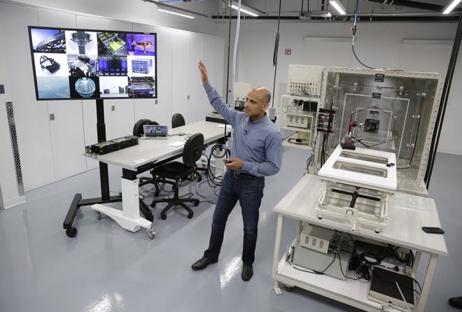 In this photo taken Tuesday, Aug. 2, 2016, Jay Parikh, vice president of engineering, talks about Area 404, the hardware R&D lab, during a tour at Facebook headquarters in Menlo Park, Calif. At right is a wind tunnel. (AP Photo/Eric Risberg)