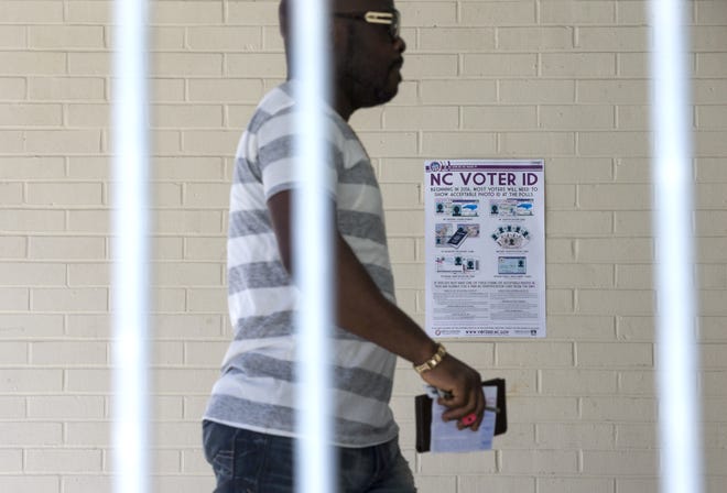 This March 15 file photo shows Eric Gandah walking past a NC Voter ID sign as he enters a precinct to cast his ballot in Greensboro. A federal appeals court on Friday blocked a North Carolina law that required voters to produce photo identification. (H. Scott Hoffmann/News & Record via AP, File)
