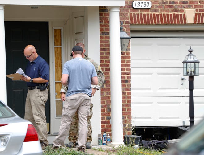 Law enforcement officers stand outside the home of Nicholas Young, a Washington Metro Transit Officer, Wednesday, Aug. 3, 2016, in Fairfax, Va., Young was arrested at Metro's headquarters in Washington and charged with a single count of attempting to provided material support to a terrorist group. (AP Photo/Pablo Martinez Monsivais)