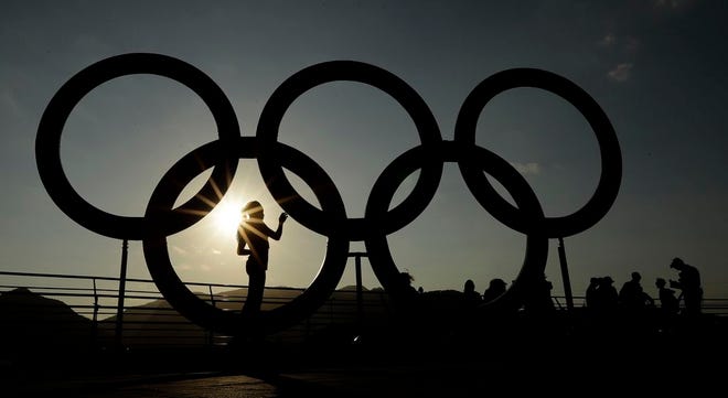 A woman is silhouetted by the setting sun as she looks at a set of Olympic rings in the Olympic Park ahead of Rio's 2016 Summer Olympics, in Rio de Janeiro, Brazil, Thursday, Aug. 4, 2016.