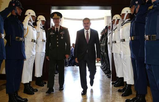 Turkey's Prime Minister Binali Yildirim, right, and the Turkey's Chief of Staff Geneneral Hulusi Akar review a honor guard before their meeting at the military headquarters in Ankara, Turkey, on Friday, Aug. 5, 2016. Turkey's state-run news agency says a court has issued a formal warrant for the arrest of U.S.-based Muslim cleric Fethullah Gulen. (Hakan Goktepe/Pool Photo via AP)