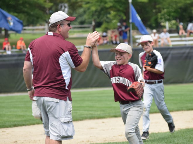 Portsmouth Little League shortstop Timmy Avery, right, gets a high-five from his father, coach Ken Avery, after Portsmouth got out of an inning against Vermont at the Eastern Region tournament in Cranston, R.I., on Saturday. Mike Zhe/Seacoastonline