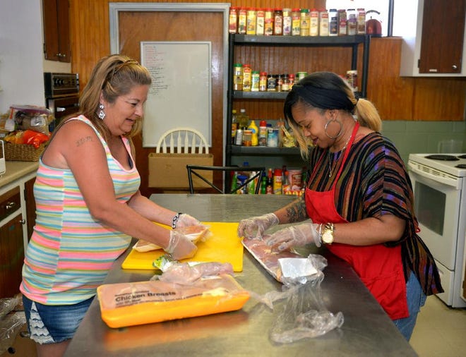 Staffer Kyatta Exum, right, with help from clubhouse member Dana prepare a chicken meal for lunchtime at the kitchen at the Reed House. (Steve Bisson/Savannah Morning News)