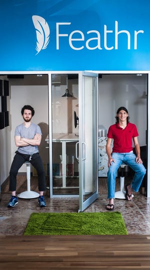 Aleksander Levental (left) and Aidan Augustin (right) sit in their new Innovation Square office. Computers, wooden tables, hanging lights, artificial turf and table tennis furnished the space. Photo by Deshlee Ford / Correspondent