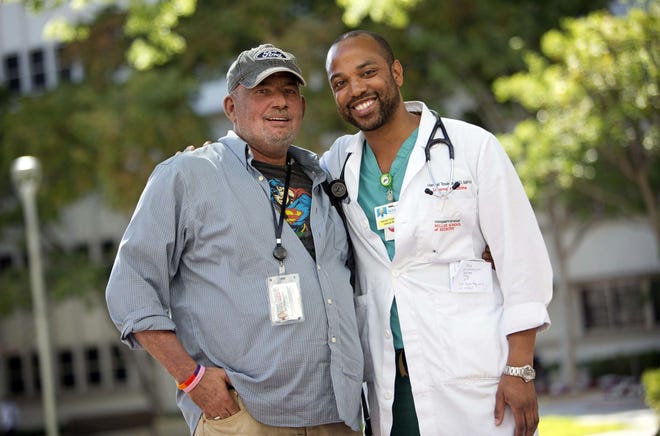 Jose De Lemos, 53, and Dr. Hansel Tookes, a University of Miami medical resident, outside of Jackson Memorial Hospital after a recent visit. De Lemos, who has HIV, is being treated by Tookes. Tookes has been leading the fight to help reduce HIV infections by starting a new needle exchange pilot program in Miami-Dade, a program that took him four years to get the Legislature to allow.  (Emily Michot/The Miami Herald via AP)