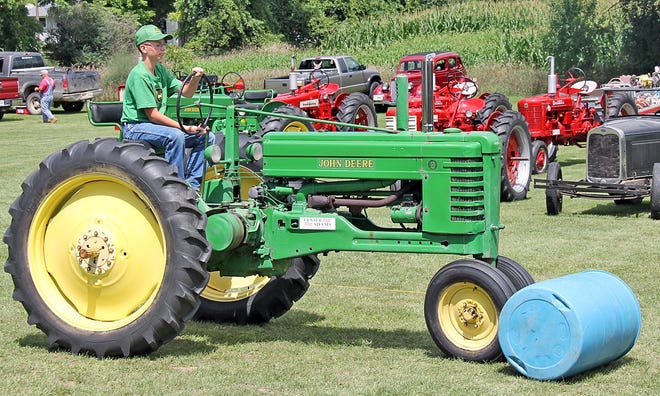 Garrett Rogers, 13, of Osseo, uses his tractor to push a barrel across the field in one "silly" race Saturday afternoon. Rogers is the youngest member of the Center Adams Antique Power Equipment Club. COREY MURRAY PHOTO