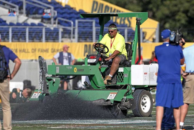 The ground crew at Tom Benson Hall of Fame Stadium scrape the painted logo off the center of the field before an NFL preseason football game between the Green Bay Packers and the Indianapolis Colts, Sunday, Aug. 7, 2016, in Canton, Ohio. (AP Photo/Ron Schwane)