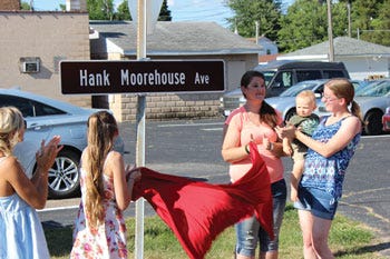 Grandchildren of the late Hank Moorehouse unveil a sign dedicating East Murray Avenue in White Pigeon to the honor of the beloved magician.
