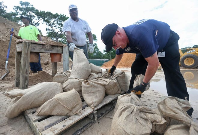 From right, Capt. Darrell Hernandez closes bags of sand as Otis Harris and Vincent Jones fill bags. Lynn Haven firefighters, city workers and volunteers filled thousands of bags of sand Monday and Tuesday at Lynn Haven Public Works.