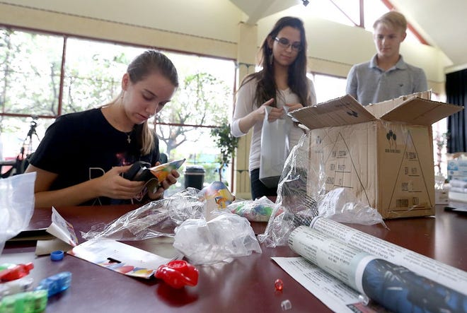 From left, 14-year-old Kat Akulova, 17-year-old Jessica Thompson and 16-year-old Tanner Pons work together to fill goodie bags. Volunteers filled hundreds of goodie bags on Aug. 9 for the Rocky Horror Picture Show at the Martin Theatre.