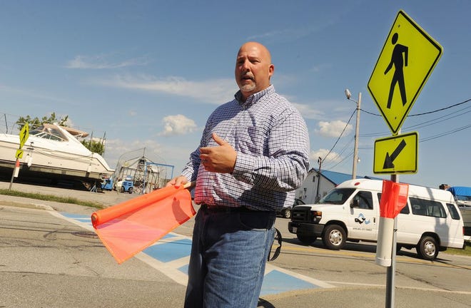 Somerset Highway Superintendent Brian Martin explains how the crosswalk flags work, at the Riverside Avenue crossing where the first set has been installed.