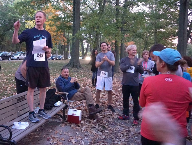 Journal columnist Ed Fitzpatrick, standing on the bench, talks to the participants of the Billy Mal 5K in Providence in October 2015. The race raised money for ALS research and to help Journal reporter Bill Malinowski as he battled ALS. Malinowski is seated next to the bench. Photo courtesy of Anne Peters.