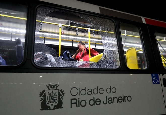 In this Aug. 9 file photo, a member of the media stands near a shattered window on a bus in the Deodoro area of Rio de Janeiro, Brazil at the 2016 Summer Olympics. Two windows where shattered when rocks, or possibly gunfire, hit the bus carrying journalists at the Rio de Janeiro Olympics. There were no injuries. Halfway through the Olympics, Rio de Janeiro is still struggling with a litany of problems that have underlined the challenges of taking the games away from their traditional territories, and made clear the games may not go to untested regions again in the near future.