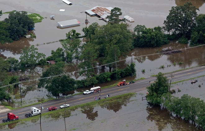 Stranded people wait on flooded U.S. Route 190 after heavy rains inundated the region Saturday. Louisiana Gov. John Bel Edwards says more than 1,000 people in south Louisiana have been rescued from homes, vehicles and even clinging to trees as a slow-moving storm hammers the state with flooding.