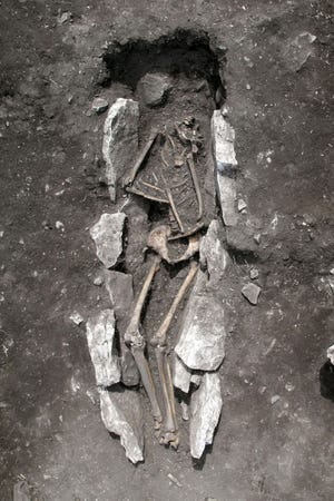This undated photo released Wednesday Aug. 10, 2016, provided by the Greek Culture Ministry, shows the 11th century B.C. skeleton of a teenager excavated recently at Mount Lykaion in the southern Peloponnese region of Greece, the mountaintop sanctuary of Zeus, king of the ancient Greek gods. Scientists are still investigating the 3,000-year old skeleton intriguingly found deep in an ash mound seemingly formed from the remains of animal sacrifices, although it is still unclear how the youth died. (Greek Culture Ministry via AP)