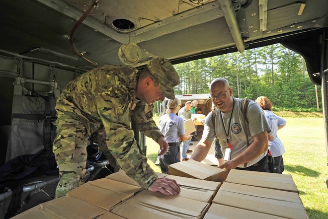Sgt. John Cooney, left, a crew chief with the N.H. Army National Guard, loads notional medical supplies onto his UH-60 Blackhawk helicopter with the help of Steven Fecteau, commander of the N.H. Metropolitan Medical Response System, during a statewide drill Aug. 5.