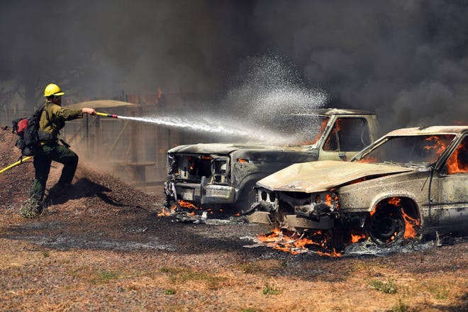 A Cal Fire firefighter douses burning cars as they burn in the town of Lower Lake, Calif., on Sunday. (AP Photo/Josh Edelson)