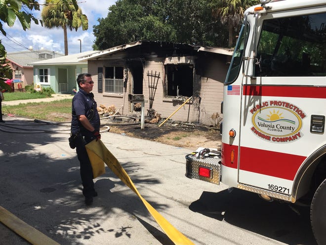 A Volusia County firefighter gathers his equipment after extinguishing a house fire on Midway Avenue in Ormond Beach on Tuesday. News-Journal/David Tucker