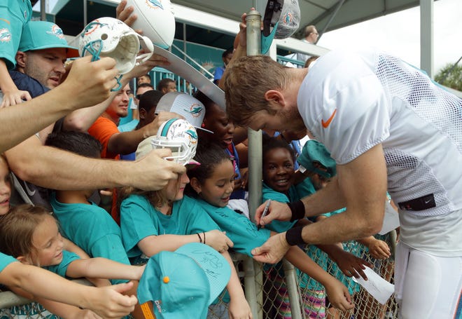 Miami Dolphins quarterback Ryan Tannehill signs autographs Tuesday after practice at training camp in Davie.
