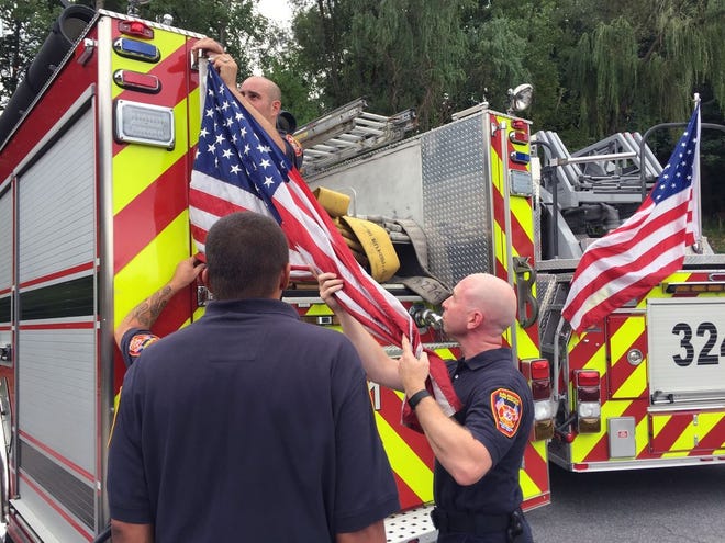 In this Tuesday, Aug. 16, 2016 photo, firefighters remove American flags from a fire truck in Poughkeepsie, N.Y.
