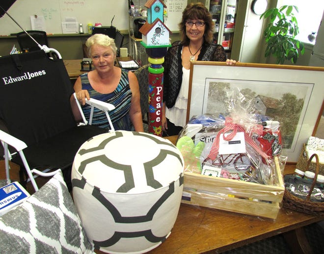 Barbara Marshall and Monica Smith of Sturgis Neighborhood Program with silent auction items donated by supporters for the SNP 25th anniversary celebration at 6 p.m. Aug. 26.