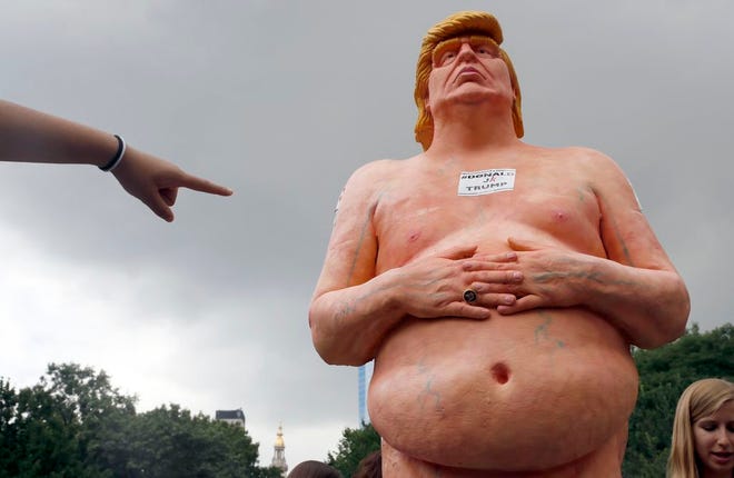 A woman points at a statue of a naked Republican presidential candidate Donald Trump, Thursday, Aug. 18, 2016 in New York's Union Square.  The statue was removed by New York City Department of Parks & Recreation employees. (AP Photo/Mary Altaffer)
