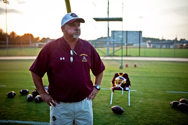Lumberton High School Football Coach, Mike Brill, watches his team warm up before a game Friday, September 17, 2010 at Cape Fear High School. The jersey and helmet behind him are set out for the late James "Rod" Anderson, a player Brill coached. Staff photo by Ashley Cross