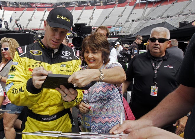 Carl Edwards signs an autograph as he walks through the pit area after practice for a NASCAR Sprint Series auto race on Friday, Aug. 19, 2016 in Bristol, Tenn. (AP Photo/Wade Payne)
